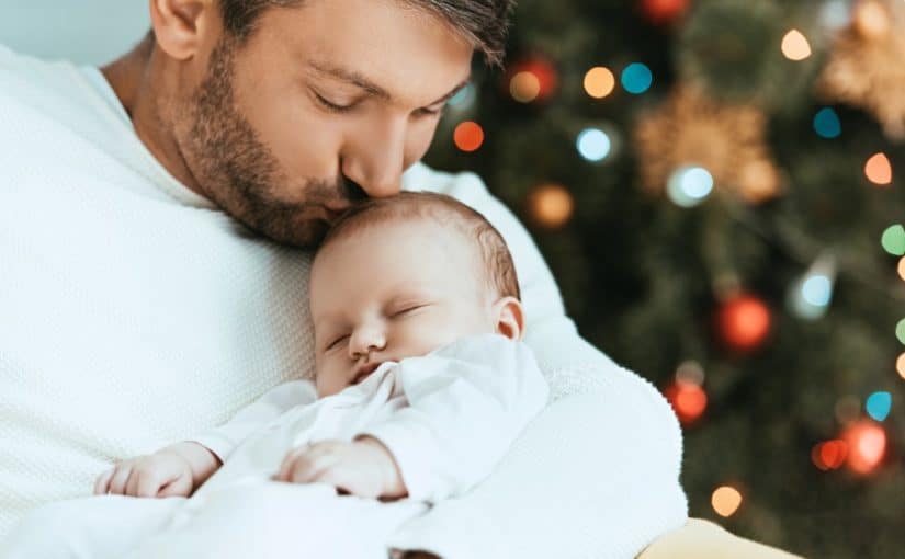 Far og baby foran et juletræ